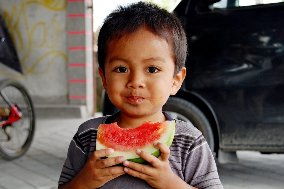 A young boy eating water melon