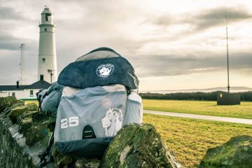Close up of a backpack with a lighthouse behind