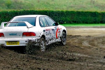 A rally car skidding around a mud track