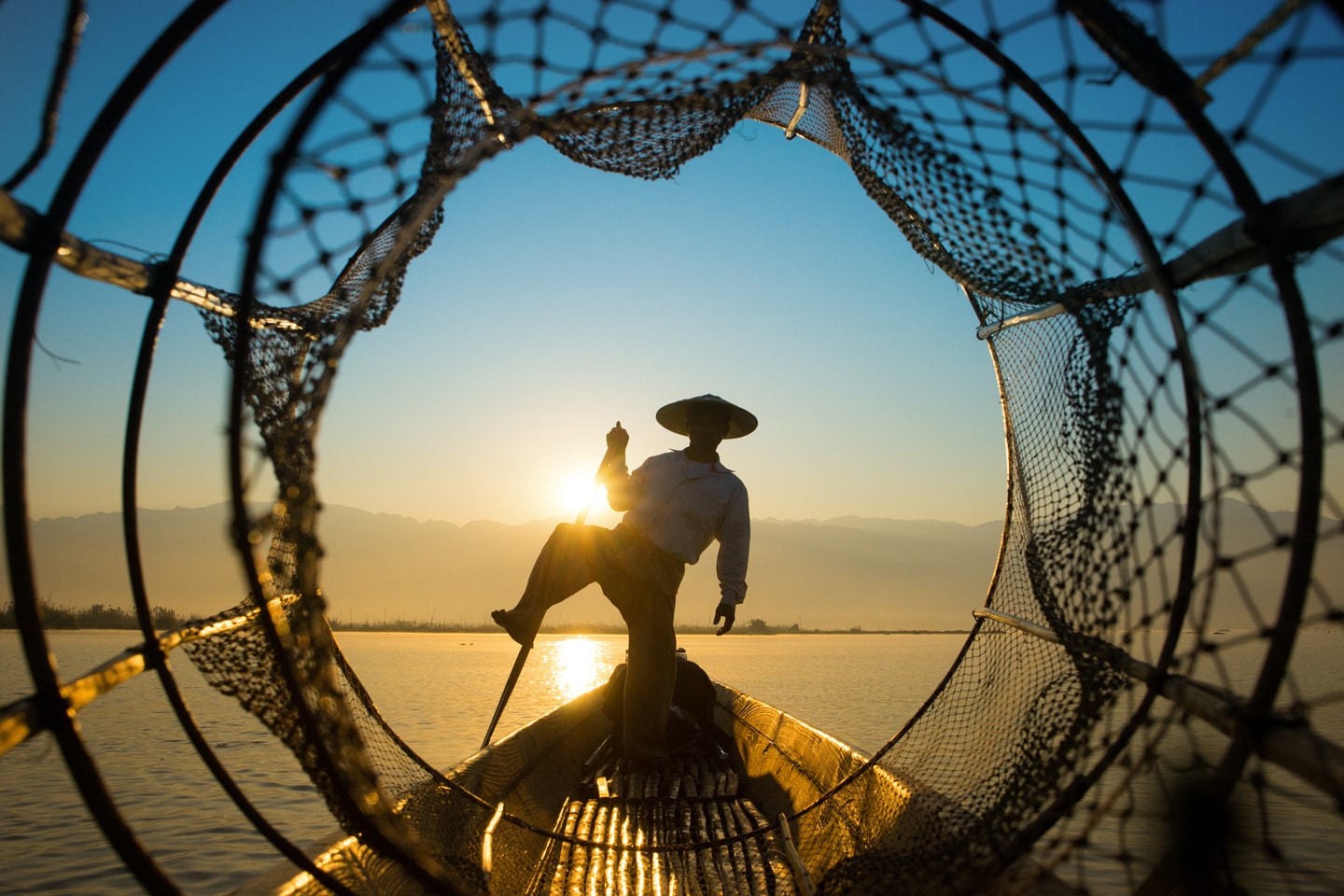 Fisherman shot through a net in Myanmar