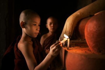 Small child lights a candle in Myanmar