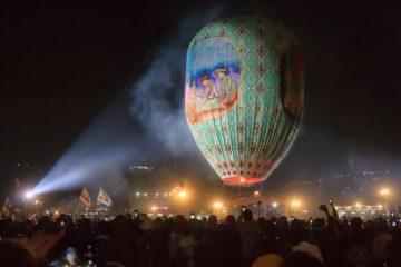 huge balloon floating in night sky with lights behind myanmar