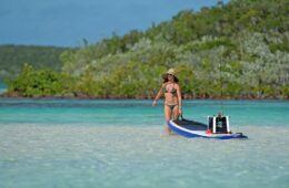 A woman in bikini on pulling a paddle board with fishing gear